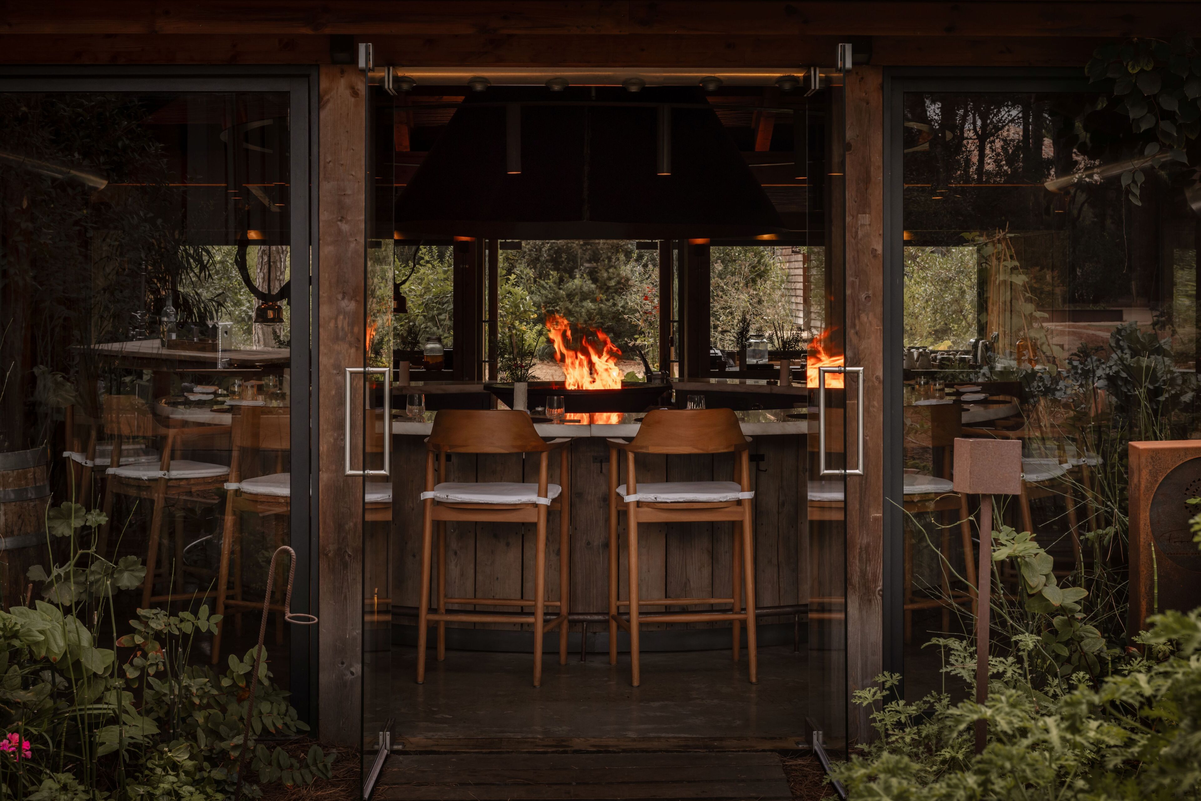 Zona de bar con chimenea, sillas de madera y vistas a través de amplios ventanales.