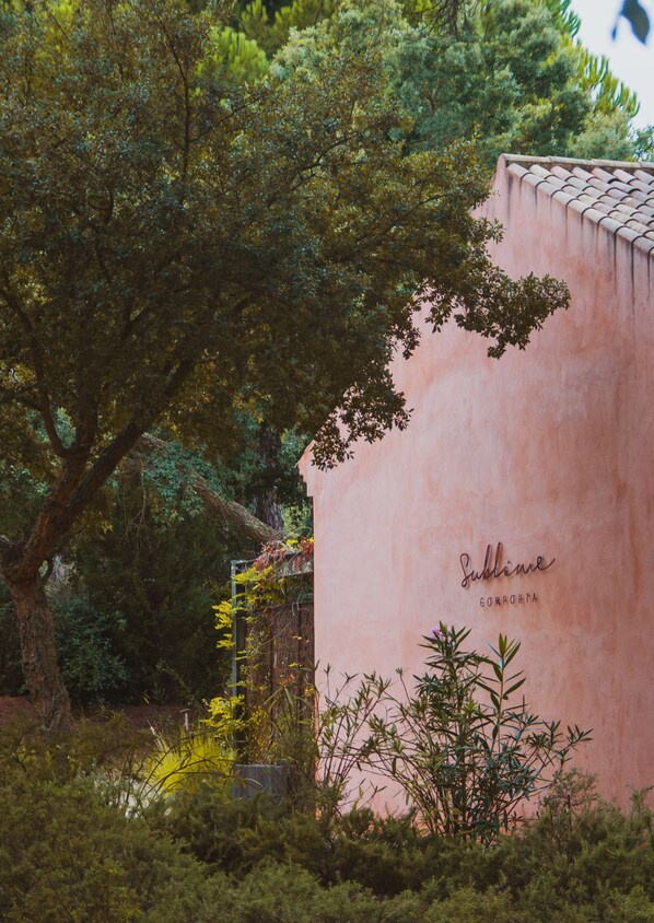 A building with a pink facade and a tree in front. - Sublime Comporta (Grandola)