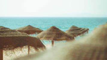 A beach with straw umbrellas and the sea in the background.