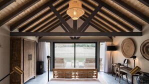 Un dormitorio con una cama grande, vigas de madera en el techo y vistas al exterior.