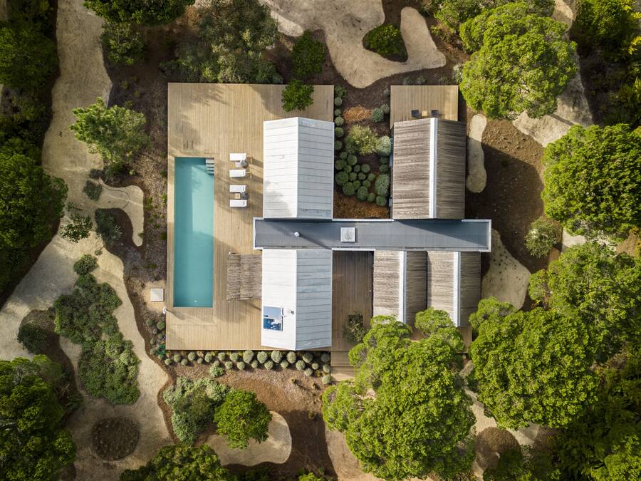 Vista aérea de una casa moderna con piscina, mobiliario de exterior y jardín.