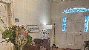Un coin repas avec une table ronde en bois, un vase de fleurs, une lampe et un tapis à motifs.