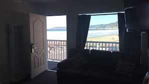 Een kamer met uitzicht op het strand, een deur en een plafondventilator.