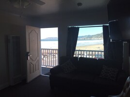 A room with a view of the beach, a door, and a ceiling fan.