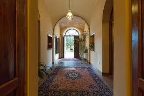 A hallway with a patterned carpet, wooden doors, and a hanging light fixture. - Corte dei Tini (Teramo)