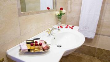 A bathroom with a white sink, a mirror, and a vase with white and red flowers.