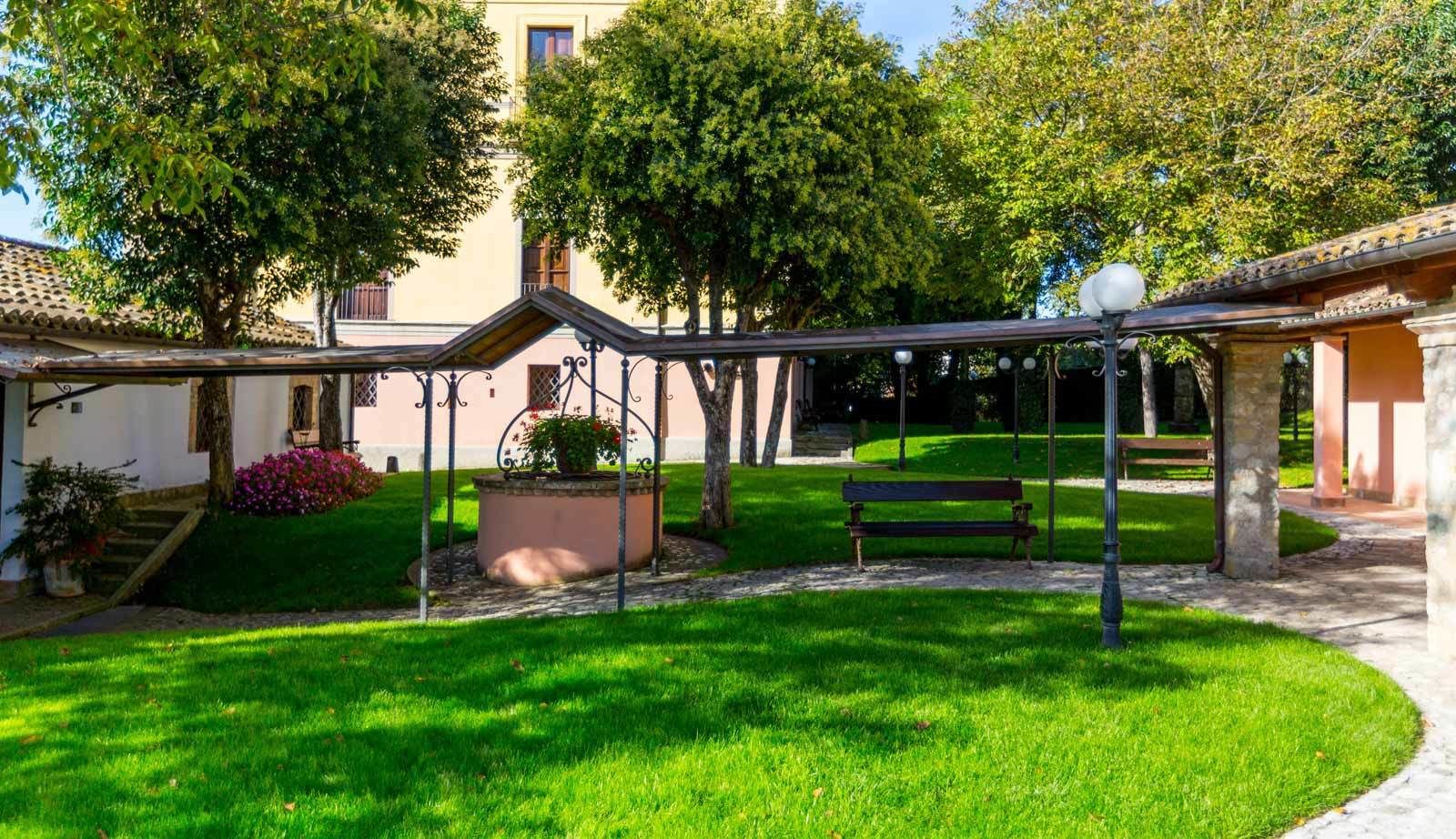 A courtyard with a bench, a pergola, and a building with a tiled roof.