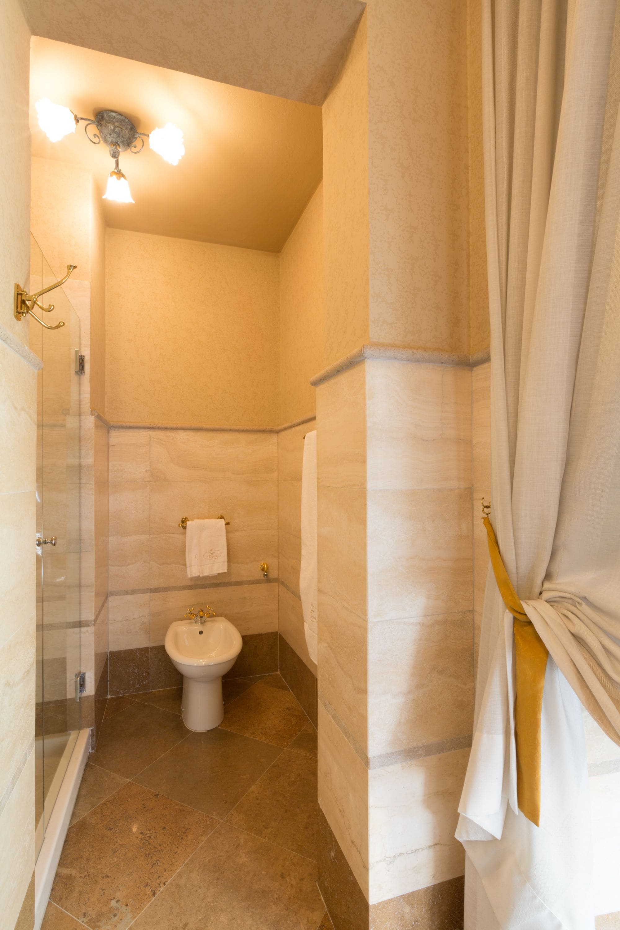 A bathroom with a glass shower enclosure, a white toilet, and a bidet.