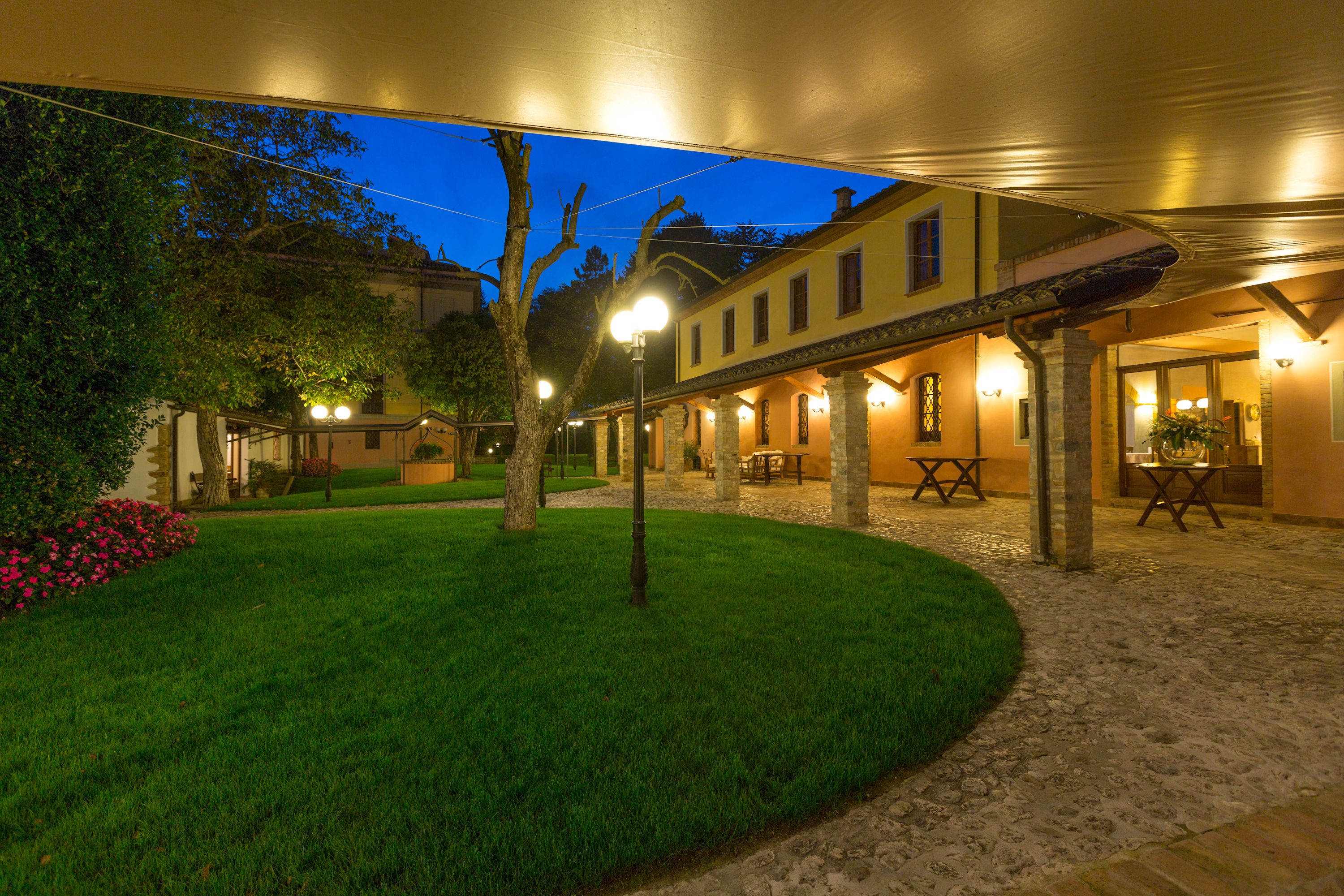 A courtyard with a well-maintained lawn, outdoor seating, and a building with multiple windows and a covered area.