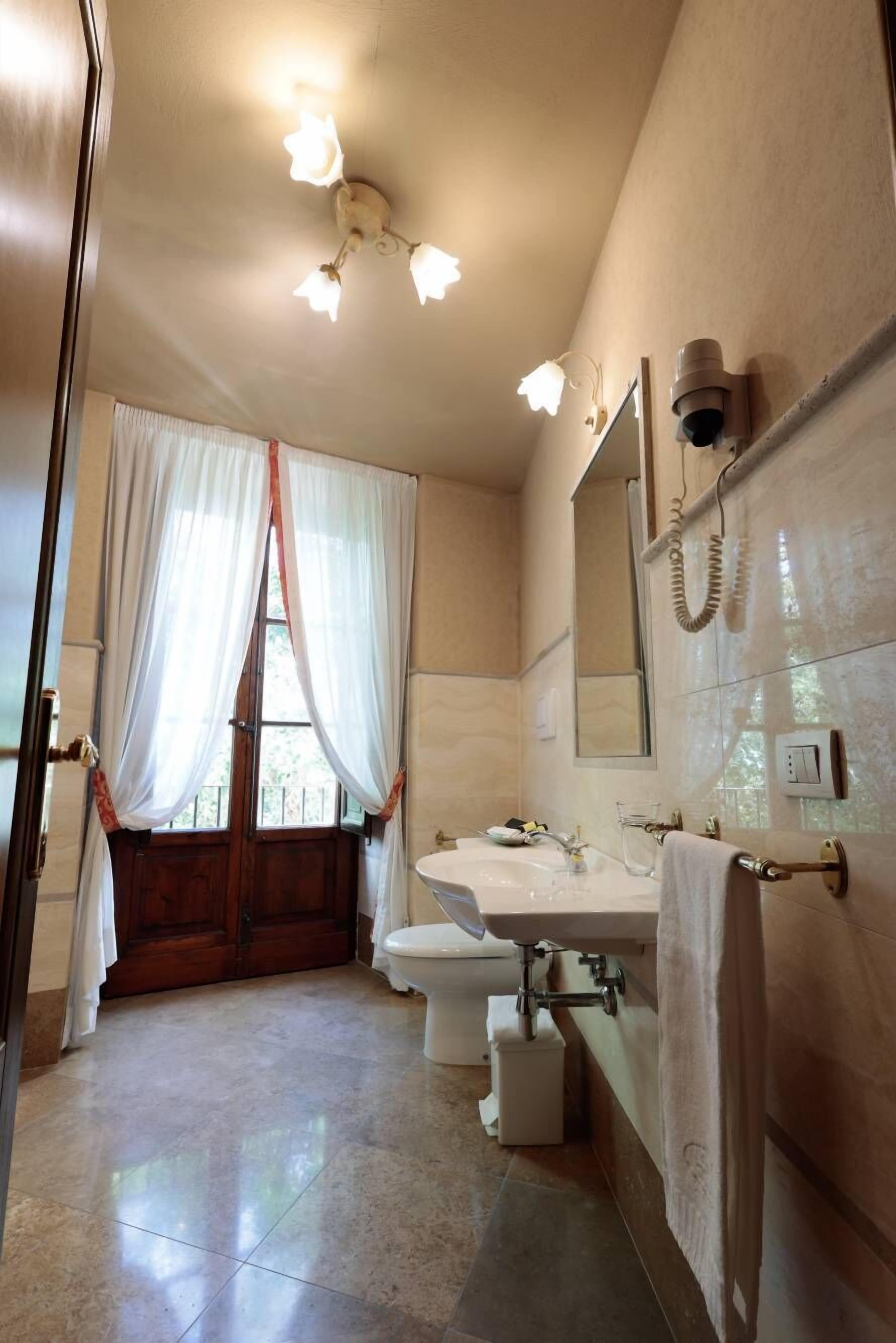 A bathroom with a toilet, sink, and mirror.