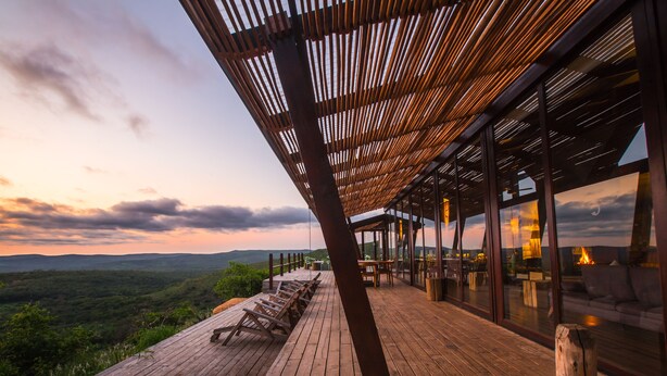 Eine Holzterrasse mit Liegestühlen mit Blick auf eine malerische Landschaft.