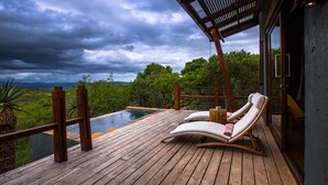 Eine Holzterrasse mit Pool, Liegestühlen und Blick auf die Landschaft.