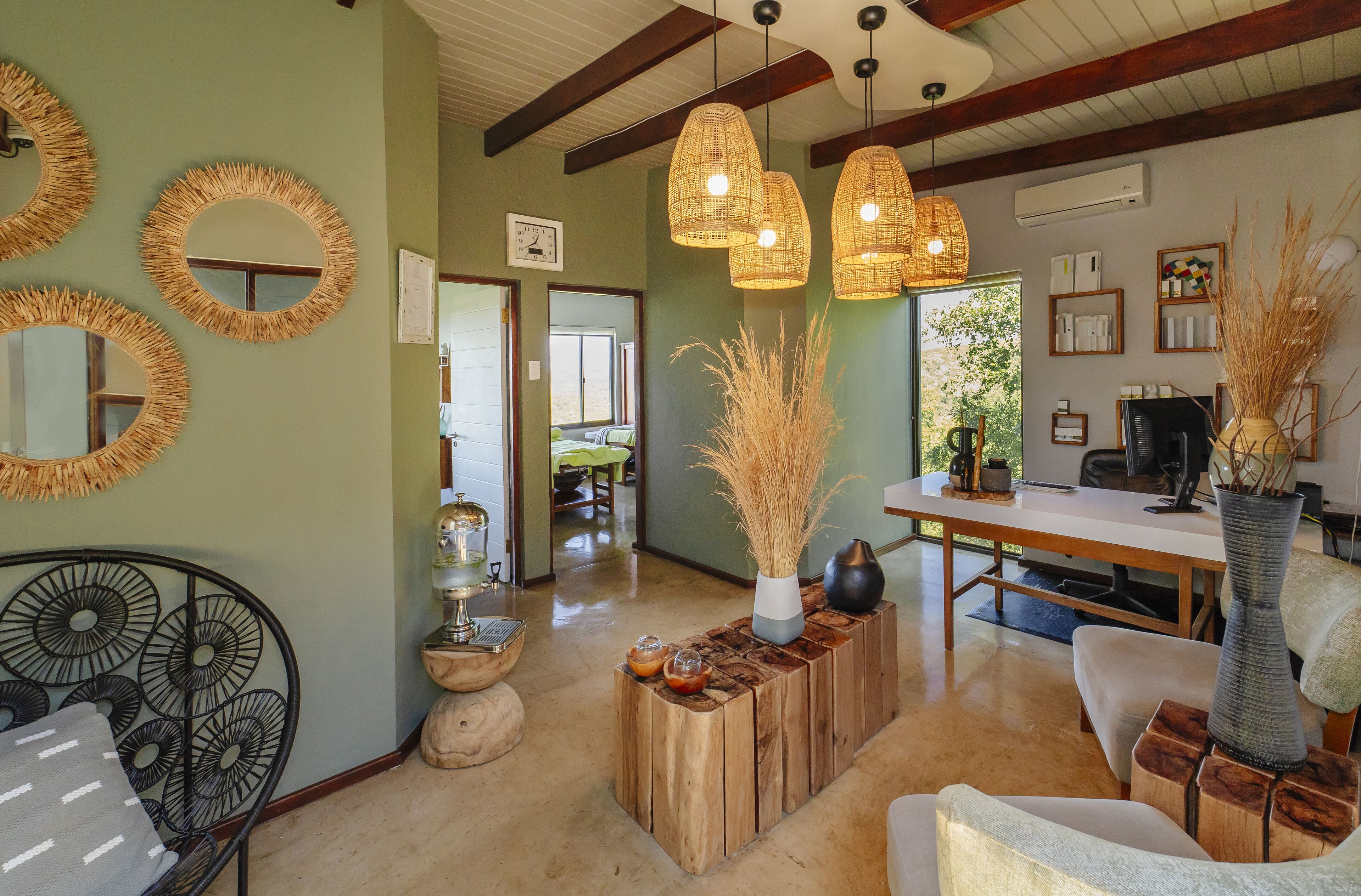A room with a dining table, chairs, a sofa, and a decorative mirror on the wall.