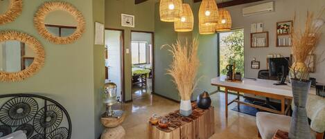 A room with a dining table, chairs, a sofa, and a decorative mirror on the wall.