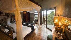 Ein Schlafzimmer mit Baldachinbett, Blick ins Freie und Holzboden.