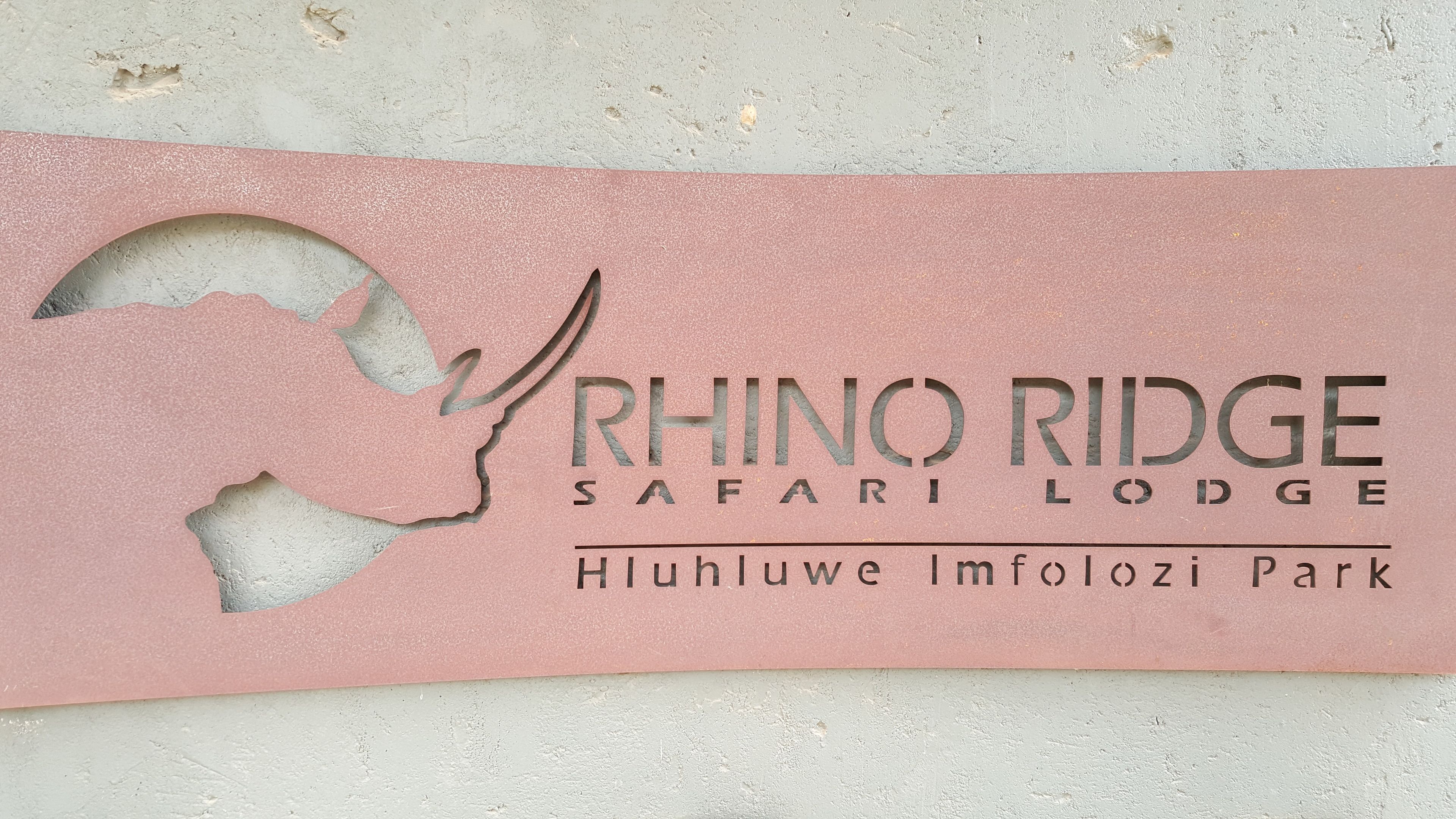 A sign for Rhino Ridge Safari Lodge with a rhinoceros silhouette and the name of the lodge.