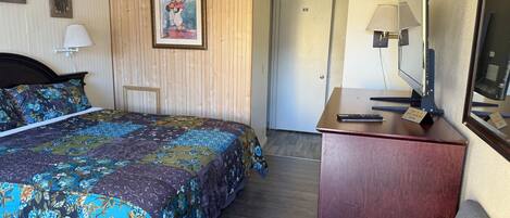 Ein Hotelzimmer mit Bett, Schreibtisch, Fernseher und einer Tür.