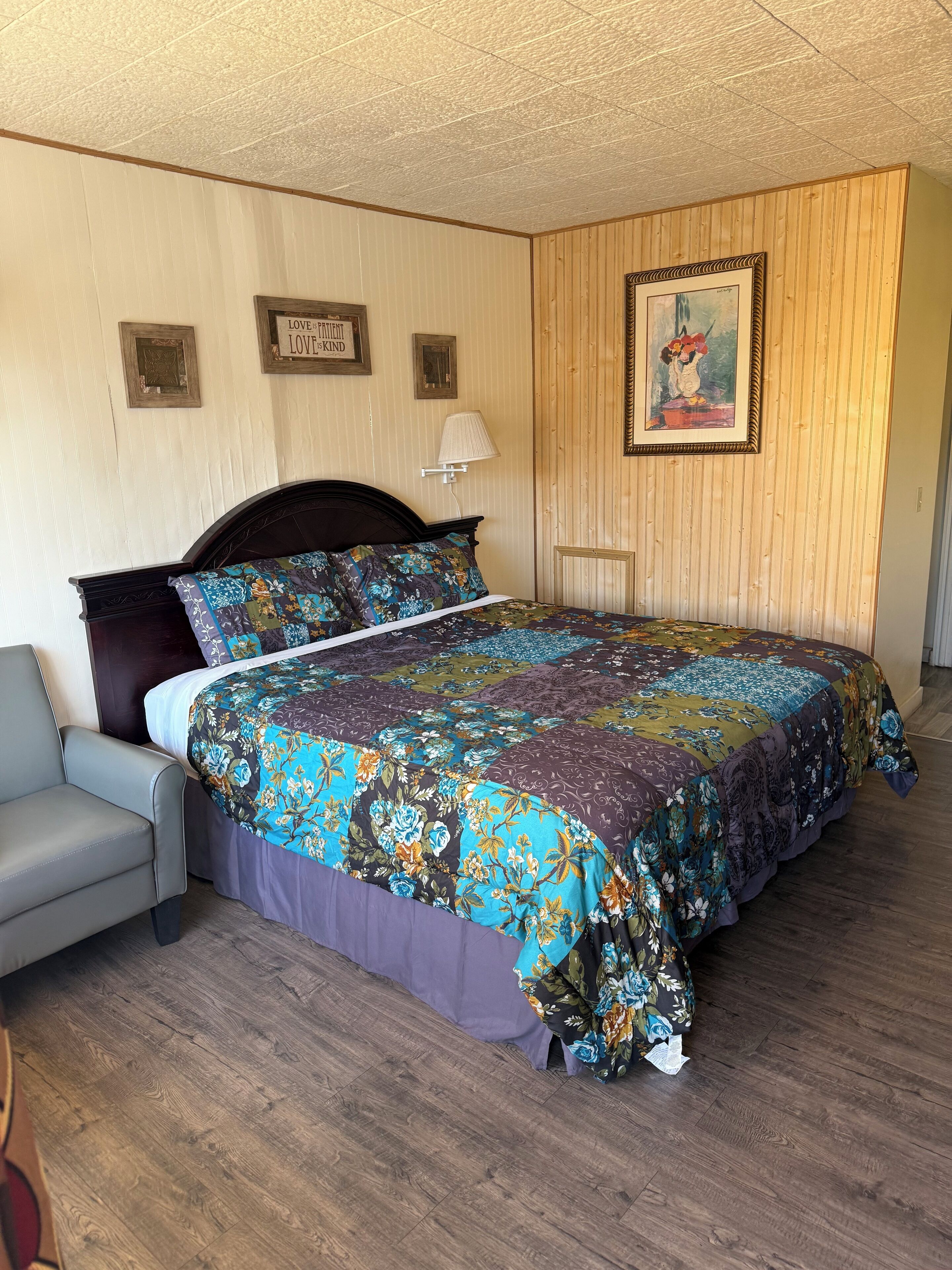 A bedroom with a bed, a chair, and a wooden wall.
