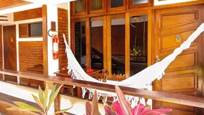 A wooden exterior with a hammock, brick walls, and a fire extinguisher. - Pousada do Frade (Ipojuca)