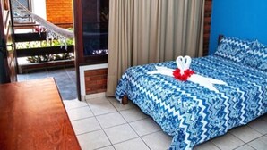 A hotel room with a bed, a wooden table, a hammock, and a view of the outdoors. - Pousada do Frade (Ipojuca)