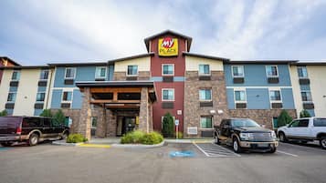 A multi-story hotel with a 'My Place' sign, parking spaces, and a covered entrance.