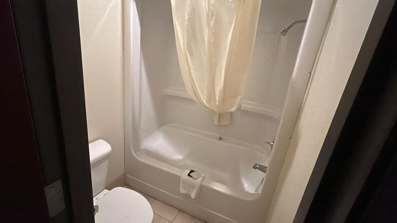 Een badkamer met een bad, toilet en douchegordijn.
