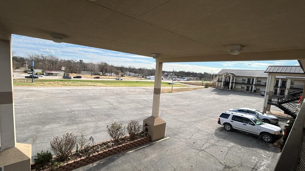 A parking lot with a white SUV parked near a building with a covered entrance.