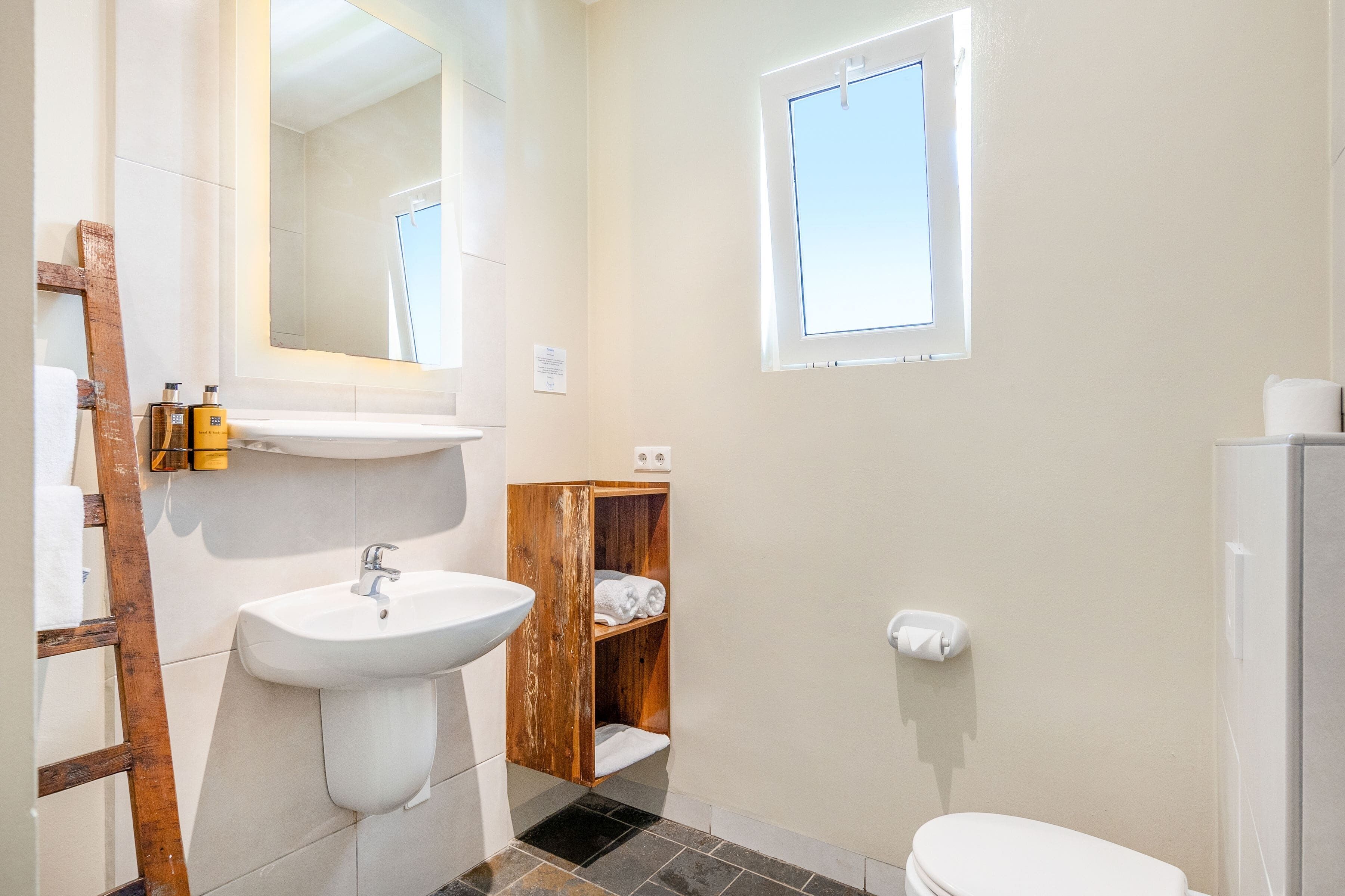 A bathroom with a white sink, wooden vanity, and a toilet.