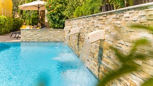 A swimming pool with a stone wall and a small waterfall feature. - Bayside Boutique Hotel - Blue Bay Golf & Beach Resort (Sint Michiel)