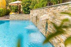 Una piscina al aire libre, sombrillas, sillones reclinables de piscina