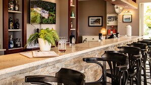 A bar area with a stone countertop, black bar stools, and a potted plant. - Bayside Boutique Hotel - Blue Bay Golf & Beach Resort (Sint Michiel)
