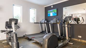Ett gym med löpband, crosstrainers och en tv-skärm på väggen.