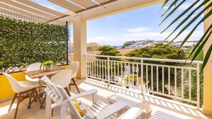 A balcony with white chairs and a table, a white railing, and a view of buildings and greenery. - Bayside Boutique Hotel - Blue Bay Golf & Beach Resort (Sint Michiel)