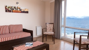 Een woonkamer met een bank, een stoel, een tafel en uitzicht op zee.