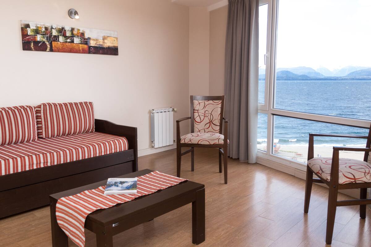 Un salon avec un canapé, un fauteuil, une table et une vue sur la mer.