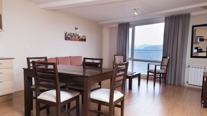 Een zithoek met een houten tafel en stoelen, een bank en uitzicht op zee.