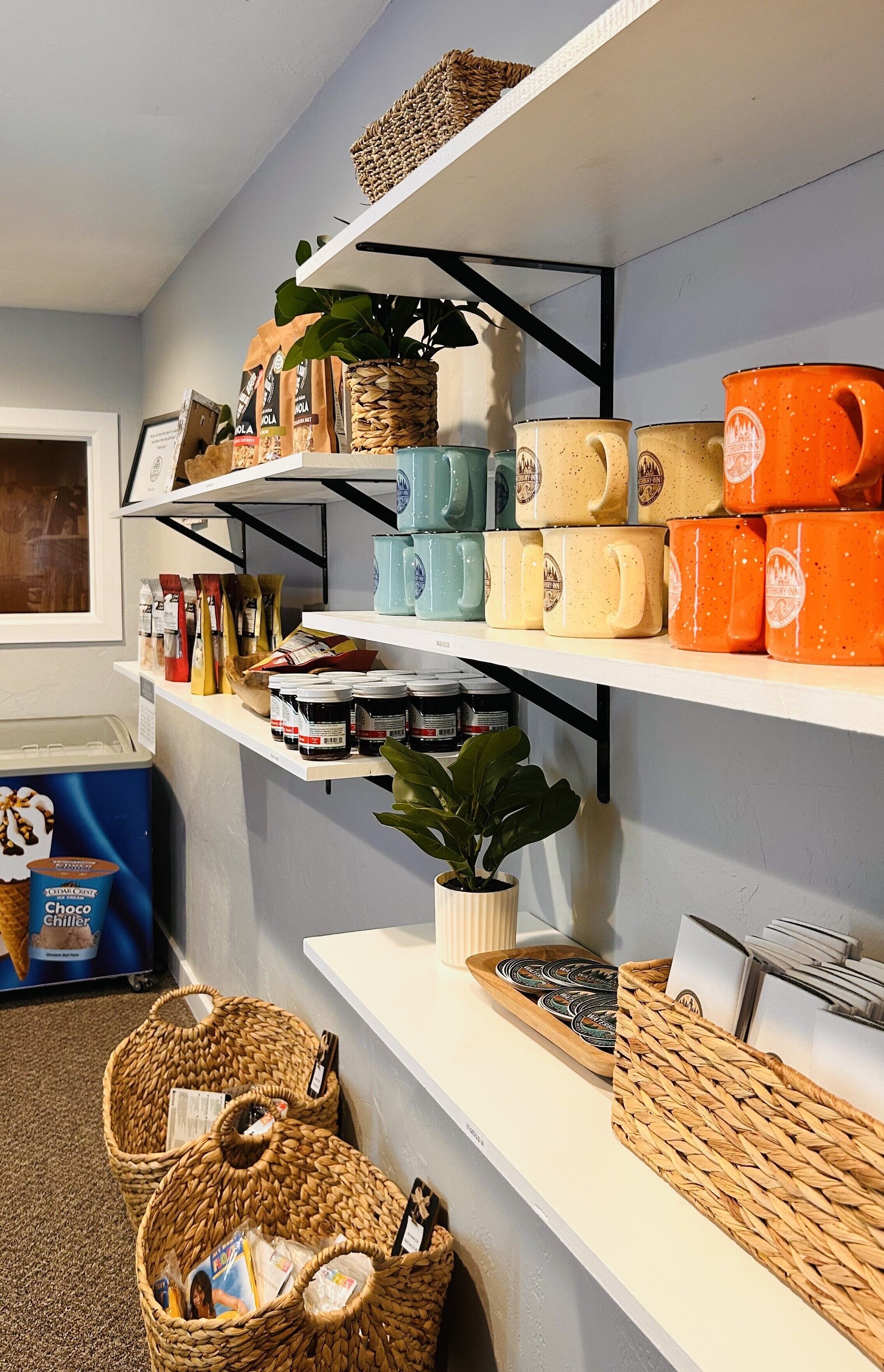 A kitchen with shelves holding various kitchenware, including mugs and jars. There are also baskets and a plant on the counter.