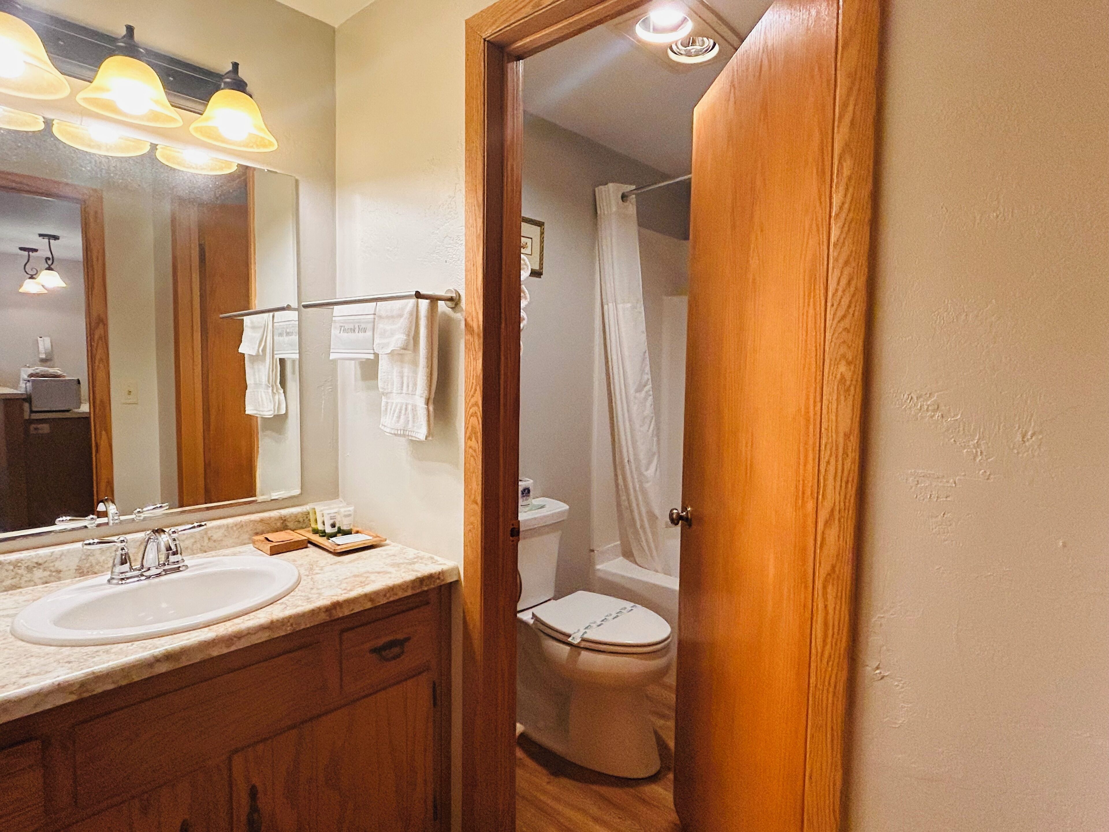 A bathroom with a wooden vanity, a large mirror, and a shower curtain.