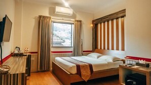 A hotel room with a bed, a desk, a chair, a TV, and a window with curtains. - Hotel 63 (Yangon)