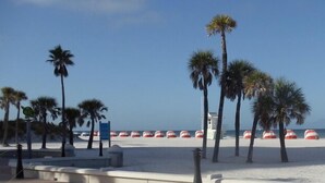 Een strand met palmbomen, strandparasols en een uitkijktoren voor de badmeester.