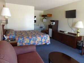 A hotel room with a bed, a desk, a dresser, a television, and a couch. - National 9 Inn Garden City (Garden City)