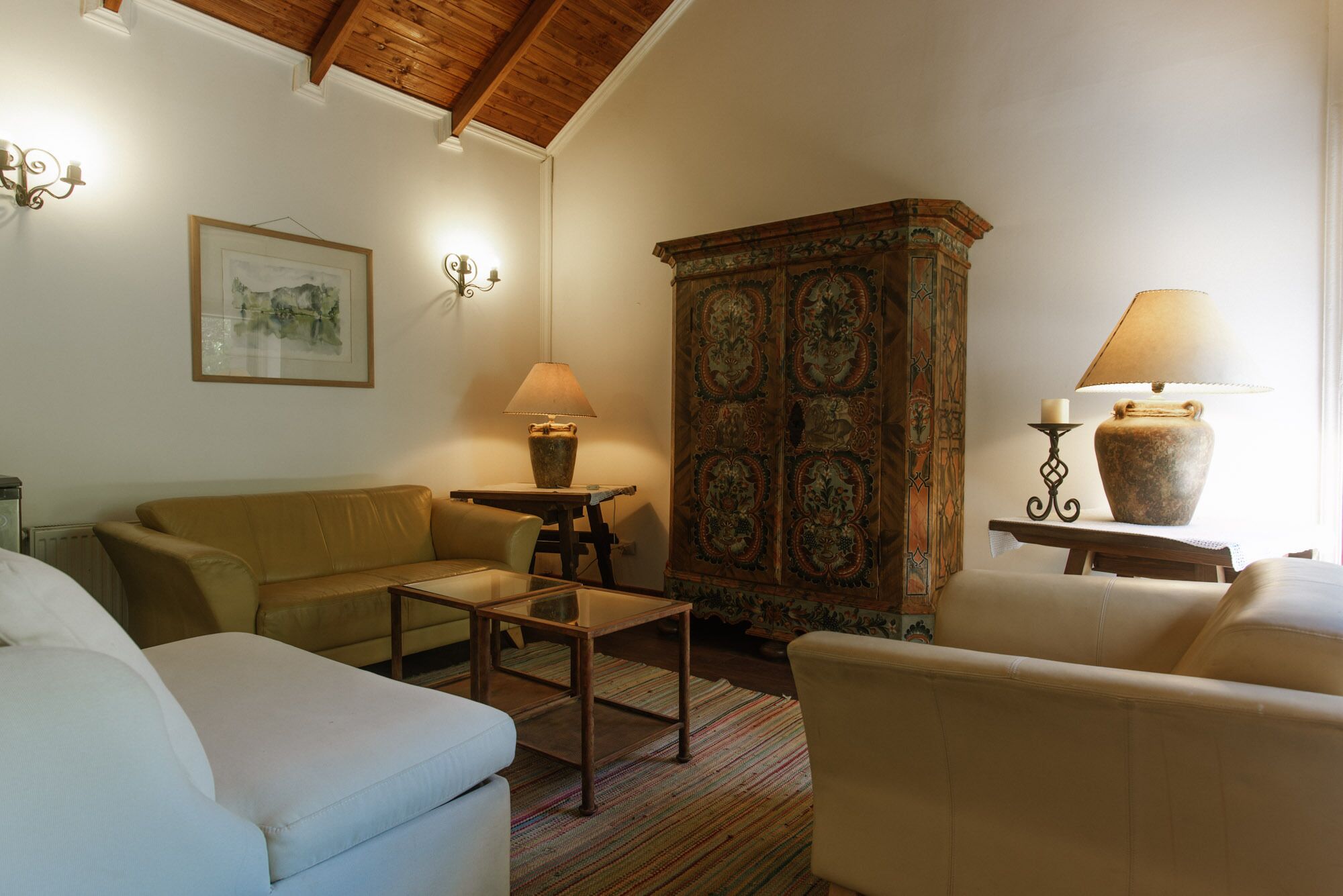 Una sala de estar acogedora con techo de madera, un mueble grande, un sofá, una mesita de centro y una lámpara.