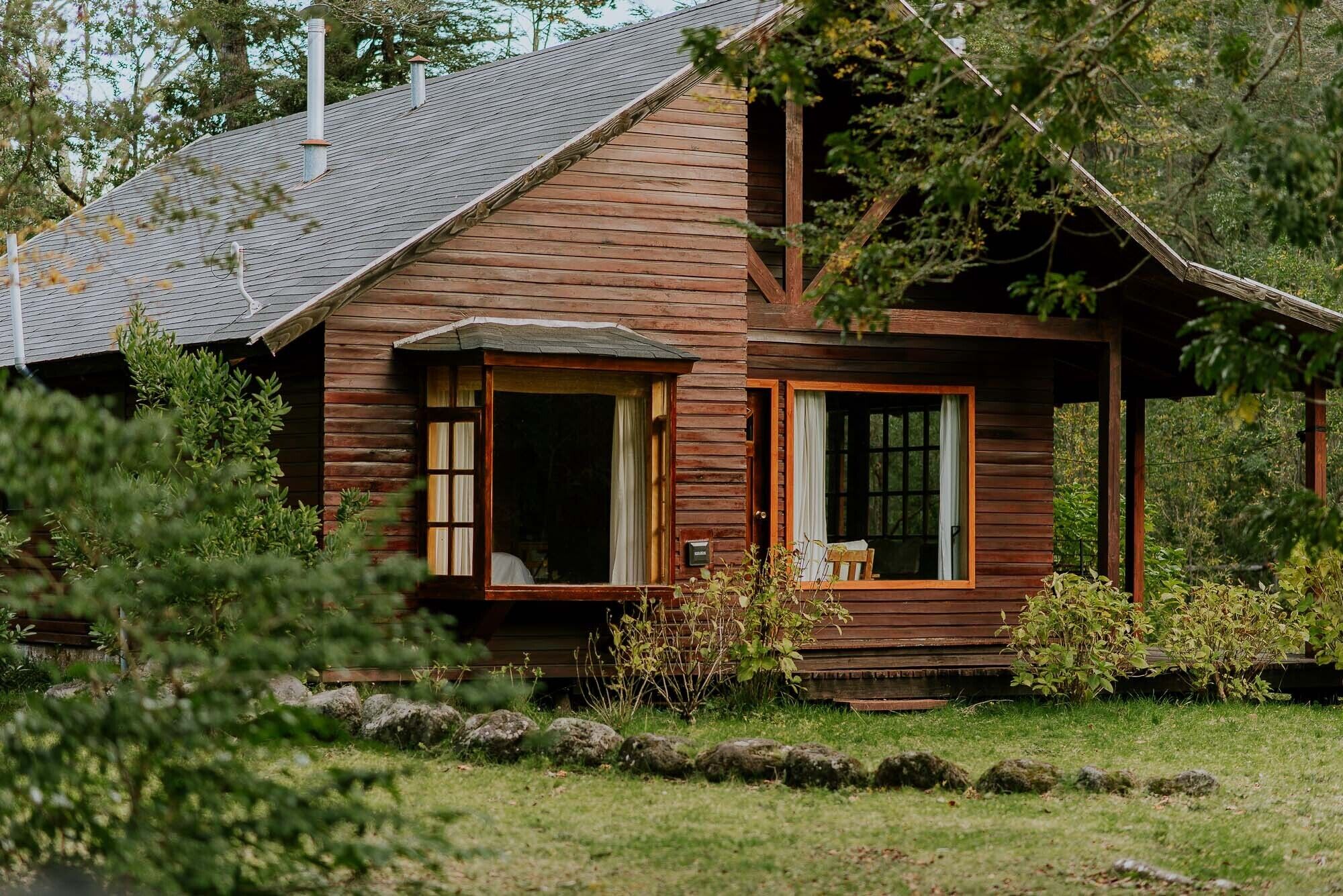 Eine rustikale Holzhütte mit geneigtem Dach, einer Veranda und einem kleinen Fenster.