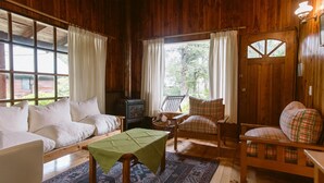 A cozy cabin interior with a sofa, armchairs, a table, and a fireplace. - Cabañas Metreñehue (Pucón)
