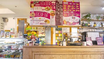 Un comptoir de produits alimentaires avec un tableau affichant le menu, divers produits et une sélection de boissons en bouteille.