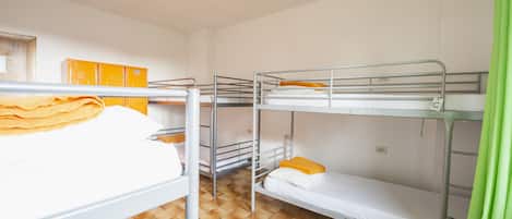 Un dormitorio con literas, una mesa y un armario.