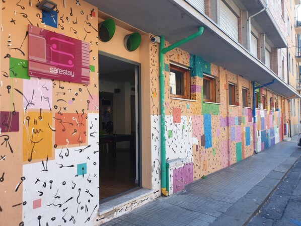 A building with colorful, abstract wall art and a visible entrance. - Safestay Pisa Centrale (Pisa)