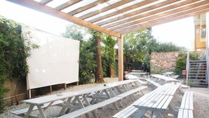 An outdoor patio with wooden picnic tables and a covered area with a wooden roof. - Safestay Pisa Centrale (Pisa)