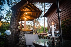 A glass table with a candle, a chair, and a stone wall in the background.