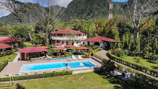 A resort with a swimming pool, multiple buildings with red roofs, and lush greenery. - Hotel y Restaurante Valle Verde (El Valle de Anton)